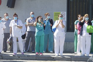 Bir Coruna-İspanya. Yeni koronavirüs kriziyle ilgilenen sağlık çalışanları, 26 Mart 2020 'de Sivil Muhafızlar ve diğer güvenlik güçleri tarafından hastanenin önünde alkışlanırken, buna karşılık alkış tutuyorlar.