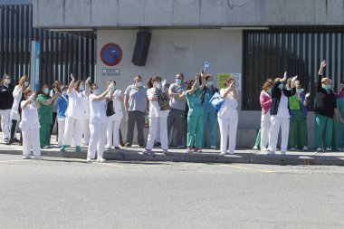 Bir Coruna-İspanya. Yeni koronavirüs kriziyle ilgilenen sağlık çalışanları, 26 Mart 2020 'de Sivil Muhafızlar ve diğer güvenlik güçleri tarafından hastanenin önünde alkışlanırken, buna karşılık alkış tutuyorlar.