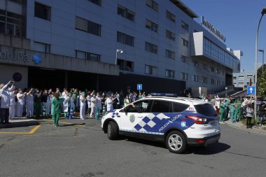 Bir Coruna-İspanya. Yeni koronavirüs kriziyle ilgilenen sağlık çalışanları, 26 Mart 2020 'de Sivil Muhafızlar ve diğer güvenlik güçleri tarafından hastanenin önünde alkışlanırken, buna karşılık alkış tutuyorlar.