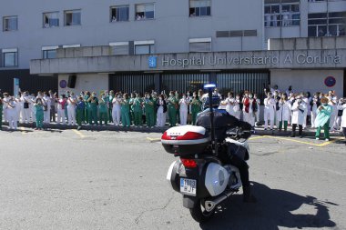 Bir Coruna-İspanya. Yeni koronavirüs kriziyle ilgilenen sağlık çalışanları, 26 Mart 2020 'de Sivil Muhafızlar ve diğer güvenlik güçleri tarafından hastanenin önünde alkışlanırken, buna karşılık alkış tutuyorlar.