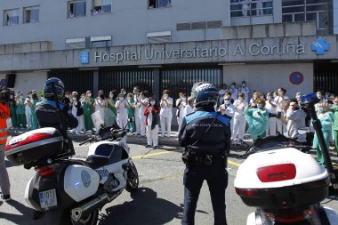 Bir Coruna-İspanya. Yeni koronavirüs kriziyle ilgilenen sağlık çalışanları, 26 Mart 2020 'de Sivil Muhafızlar ve diğer güvenlik güçleri tarafından hastanenin önünde alkışlanırken, buna karşılık alkış tutuyorlar.