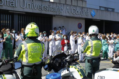 Bir Coruna-İspanya. Yeni koronavirüs kriziyle ilgilenen sağlık çalışanları, 26 Mart 2020 'de Sivil Muhafızlar ve diğer güvenlik güçleri tarafından hastanenin önünde alkışlanırken, buna karşılık alkış tutuyorlar.