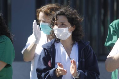 Bir Coruna-İspanya. Yeni koronavirüs kriziyle ilgilenen sağlık çalışanları, 26 Mart 2020 'de Sivil Muhafızlar ve diğer güvenlik güçleri tarafından hastanenin önünde alkışlanırken, buna karşılık alkış tutuyorlar.