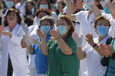 Bir Coruna-İspanya. Yeni koronavirüs kriziyle ilgilenen sağlık çalışanları, 26 Mart 2020 'de Sivil Muhafızlar ve diğer güvenlik güçleri tarafından hastanenin önünde alkışlanırken, buna karşılık alkış tutuyorlar.