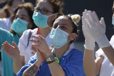 Bir Coruna-İspanya. Yeni koronavirüs kriziyle ilgilenen sağlık çalışanları, 26 Mart 2020 'de Sivil Muhafızlar ve diğer güvenlik güçleri tarafından hastanenin önünde alkışlanırken, buna karşılık alkış tutuyorlar.