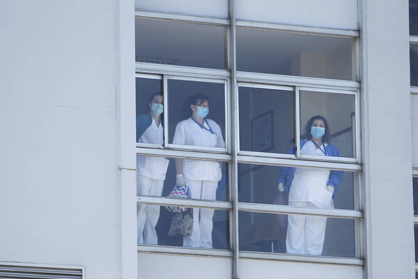 Healthcare workers dealing with the new coronavirus crisis look through the windows of the University Hospital in Coruna, northwestern Spain, on March 26, 2020