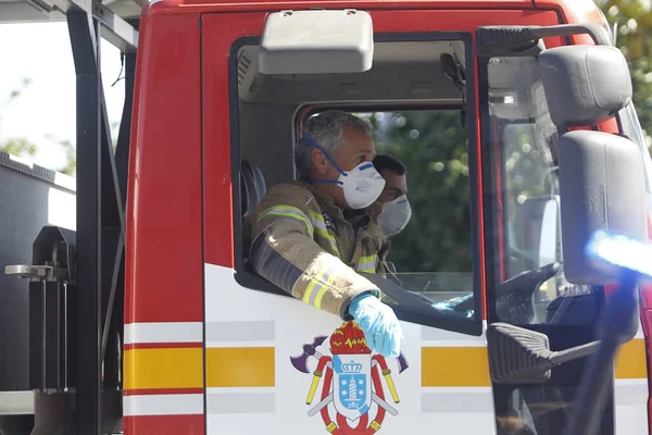 26 Mart 2020 'de İspanya' yı etkileyen koronavirüs salgınında çalışan acil durum ekiplerinin anısına maskeli itfaiyeciler itfaiye araçlarının içinde.