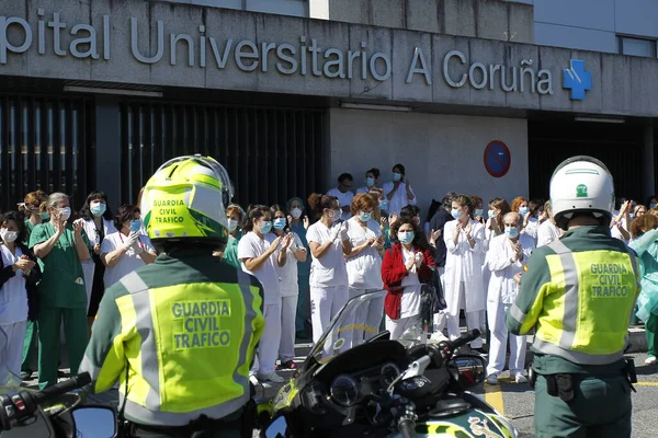 Bir Coruna-İspanya. Yeni koronavirüs kriziyle ilgilenen sağlık çalışanları, 26 Mart 2020 'de Sivil Muhafızlar ve diğer güvenlik güçleri tarafından hastanenin önünde alkışlanırken, buna karşılık alkış tutuyorlar.
