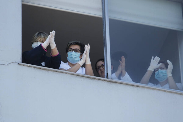 Healthcare workers dealing with the new coronavirus crisis look through the windows of the University Hospital in Coruna, northwestern Spain, on March 26, 2020