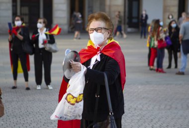 Coruna-İspanya. 19 Mayıs 2020 'deki covid-19 salgını sırasında İspanya hükümetine karşı yüz maskeli protestocu bir tencereye dokundu.