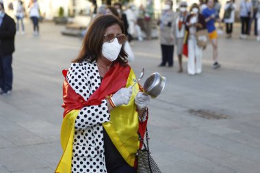 Coruna-İspanya. 19 Mayıs 2020 'deki covid-19 salgını sırasında İspanya hükümetine karşı yüz maskeli protestocu bir tencereye dokundu.