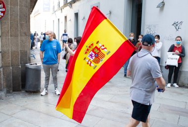 Coruna-İspanya. 19 Mayıs 2020 'de İspanyol hükümetinin yönetimine karşı yüz maskeli protestocular bir tencereye dokundular.
