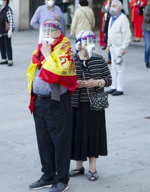Coruna-İspanya. 19 Mayıs 2020 'de İspanyol hükümetinin yönetimine karşı yüz maskeli protestocular bir tencereye dokundular.