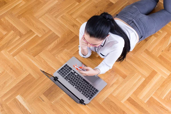 Ragazza con computer portatile e telefono sul fllor — Foto Stock