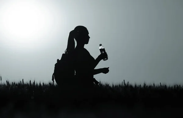 Silhouet van de vrouw met rugzak en fles water — Stockfoto