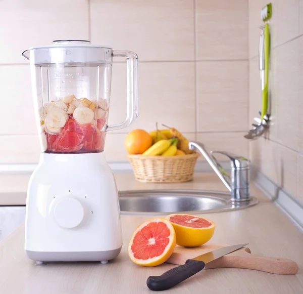 Mixer mit geschnittener Grapefruit auf Küchenarbeitsplatte — Stockfoto