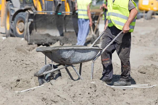 Byggnadsarbetare som skjuter skottkärra — Stockfoto