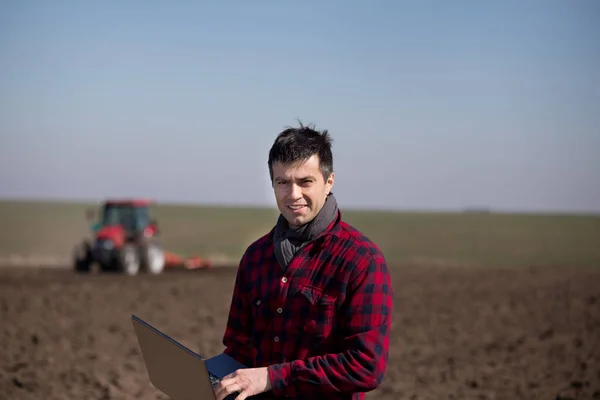 Famer med laptop och traktor i fältet — Stockfoto