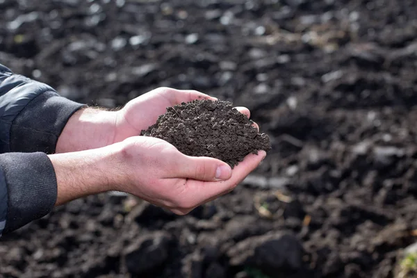 Фермер держит почву в руках в поле — стоковое фото