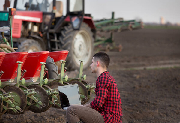 Фермер с ноутбуком и тракторами
