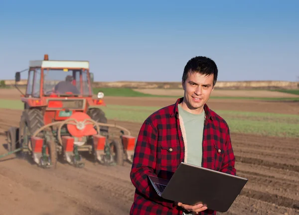 Agricultor com laptop e trator de semeadura — Fotografia de Stock