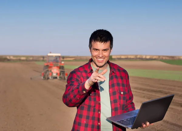 Nöjd bonde med laptop och traktor — Stockfoto