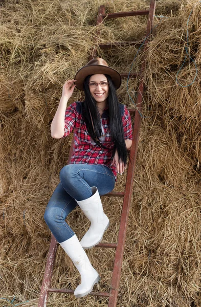 Woman leaning on laader and straw pile — Stock Photo, Image