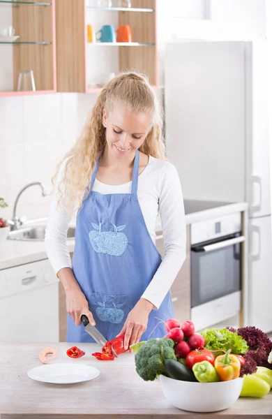 Žena řezání zeleniny v kuchyni — Stock fotografie