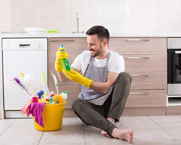 Uomo con prodotti per la pulizia in cucina — Foto Stock