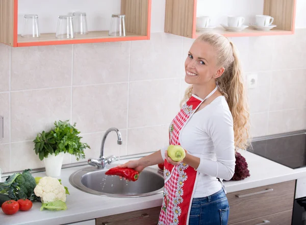 Menina lavar legumes na cozinha — Fotografia de Stock