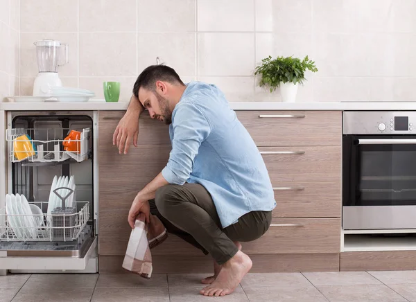 Cansado homem ao lado de máquina de lavar louça aberta — Fotografia de Stock