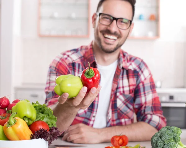 Homem mostrando legumes na cozinha — Fotografia de Stock