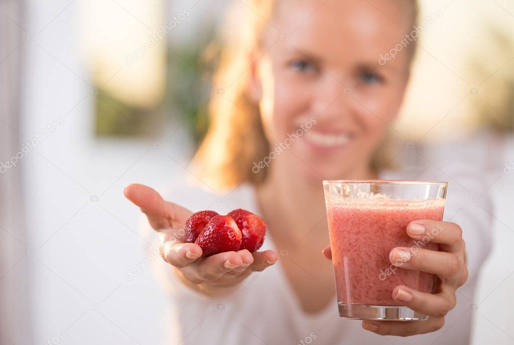 Girl holding strawberry and smoothie