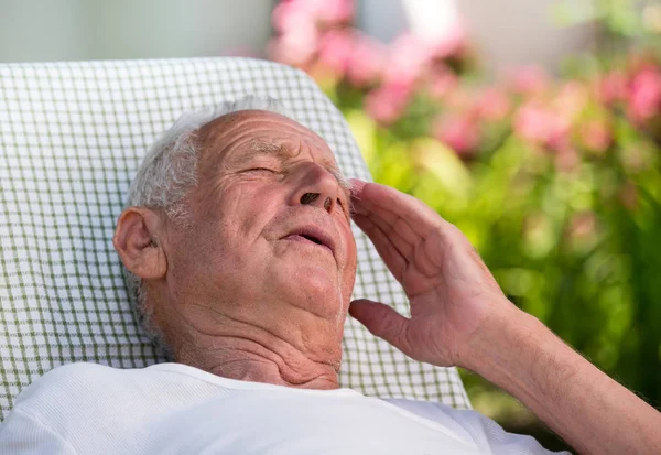 Old man having headache in garden — Stock Photo, Image