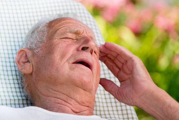 Old man having headache in garden — Stock Photo, Image