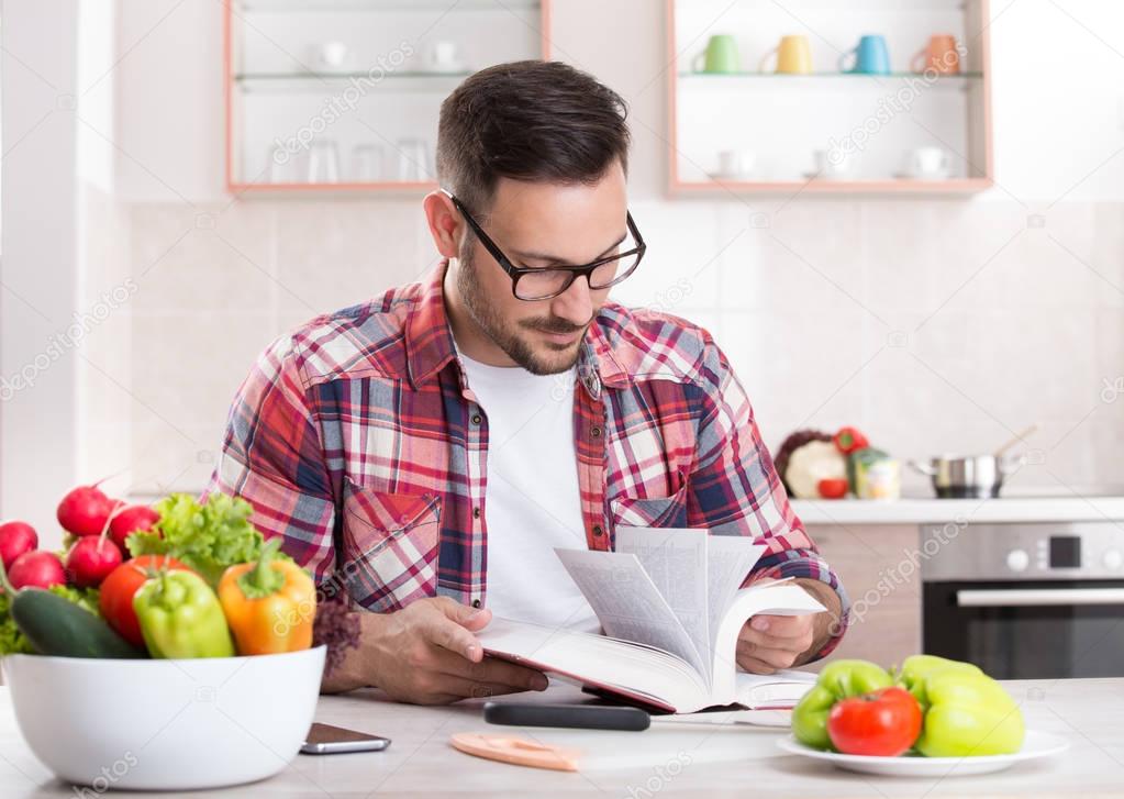 Man reading recipe book in kitchen