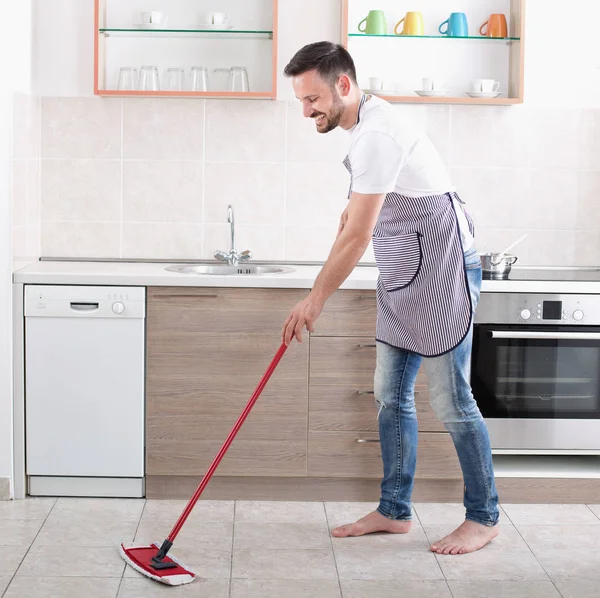 Чоловік обмотує підлогу на кухні — стокове фото
