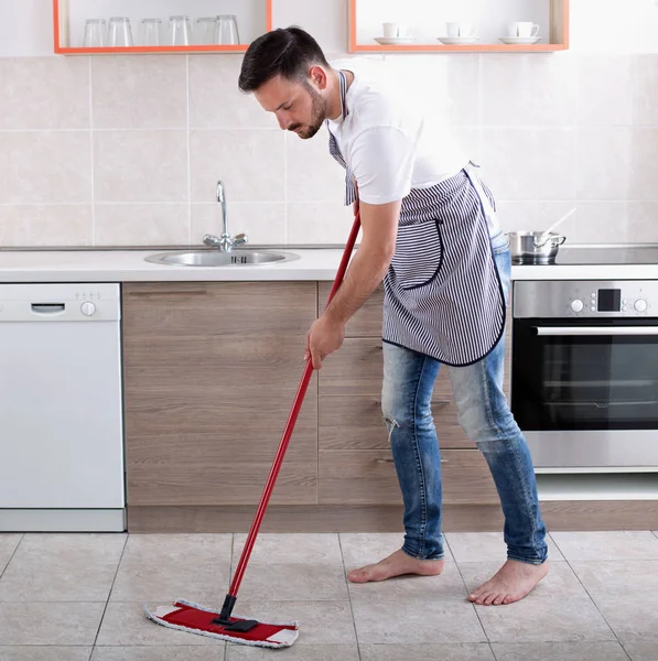 Чоловік обмотує підлогу на кухні — стокове фото