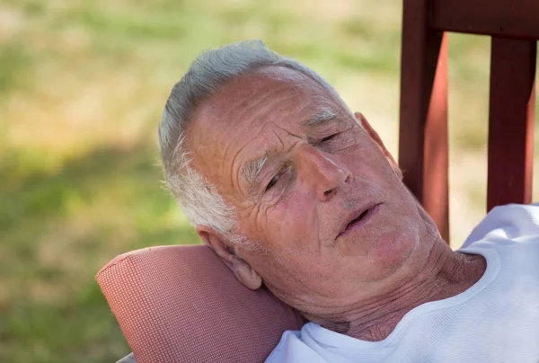 Uomo anziano sdraiato sulla panchina in giardino — Foto Stock