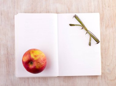 Masa üzerinde gözlük ve elma ile açık kitap