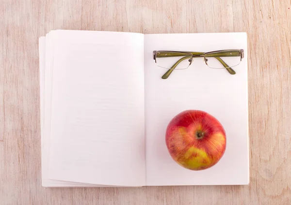 Open book with glasses and apple on desk — Stock Photo, Image
