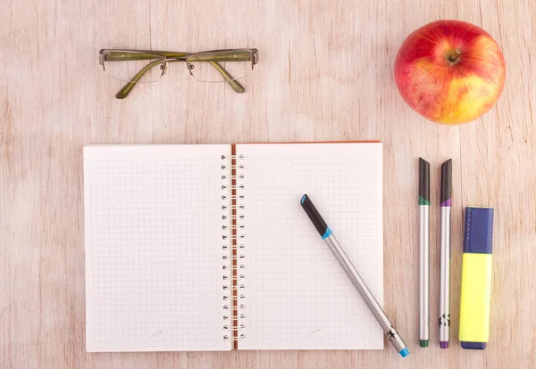 Otevřít poznámkový blok s tužky, brýle a apple na stole — Stock fotografie