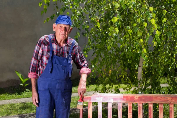 Старий малює лавку в саду — стокове фото
