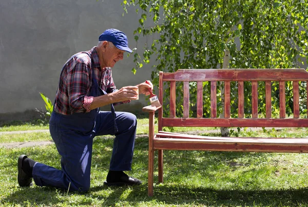 Alter Mann bemalt Bank im Garten — Stockfoto