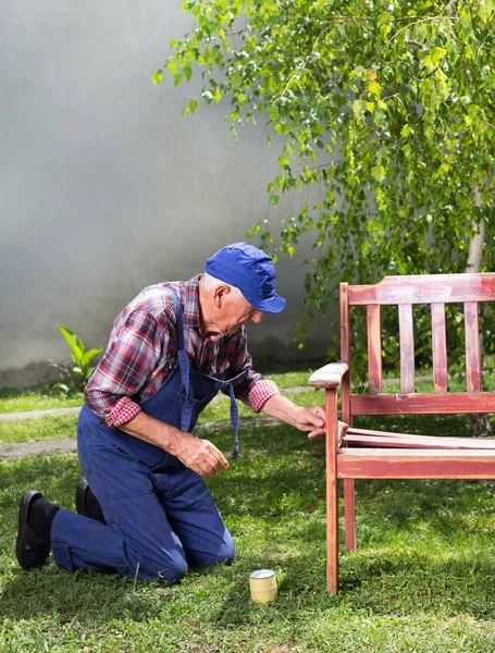 Alter Mann bemalt Bank im Garten — Stockfoto
