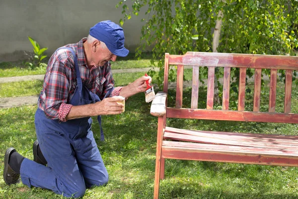 Alter Mann bemalt Bank im Garten — Stockfoto