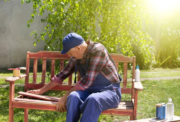 Vecchio che ripara panca in giardino — Foto Stock