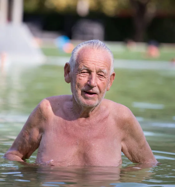 Старик отдыхает в бассейне — стоковое фото