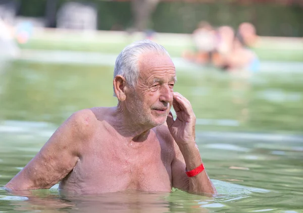 Oude man rust in zwembad — Stockfoto