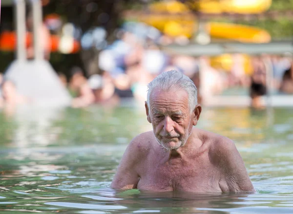 Oude man rust in zwembad — Stockfoto